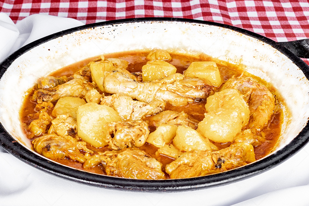 Ensopado de frango caseiro com tomate, cebola e batata na mesa de tecido preto e prato com arroz