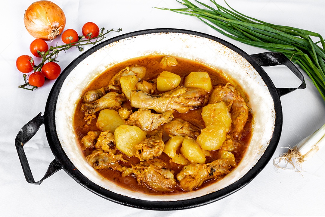 Ensopado de frango caseiro com tomate, cebola e batata na mesa de tecido preto e prato com arroz