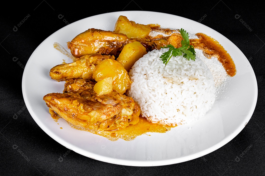 Ensopado de frango caseiro com tomate, cebola e batata em uma mesa de tecido preto e prato com arroz, feijão e suco de laranja. Vista do topo.