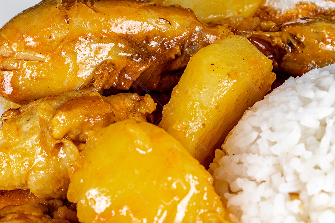 Ensopado de frango caseiro com tomate, cebola e batata em uma mesa de tecido preto e prato com arroz, feijão e suco de laranja. Vista do topo.