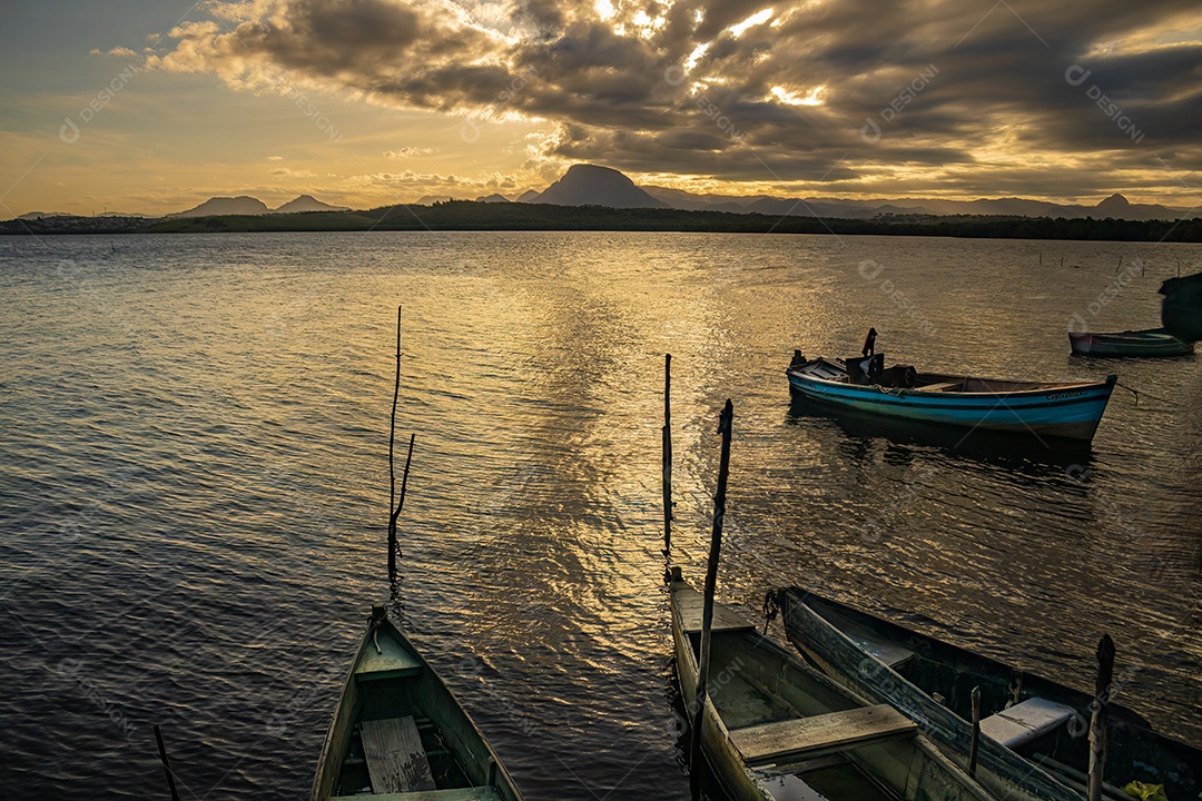 Pôr do sol com barco em primeiro plano e montanha mochuara ao fundo.