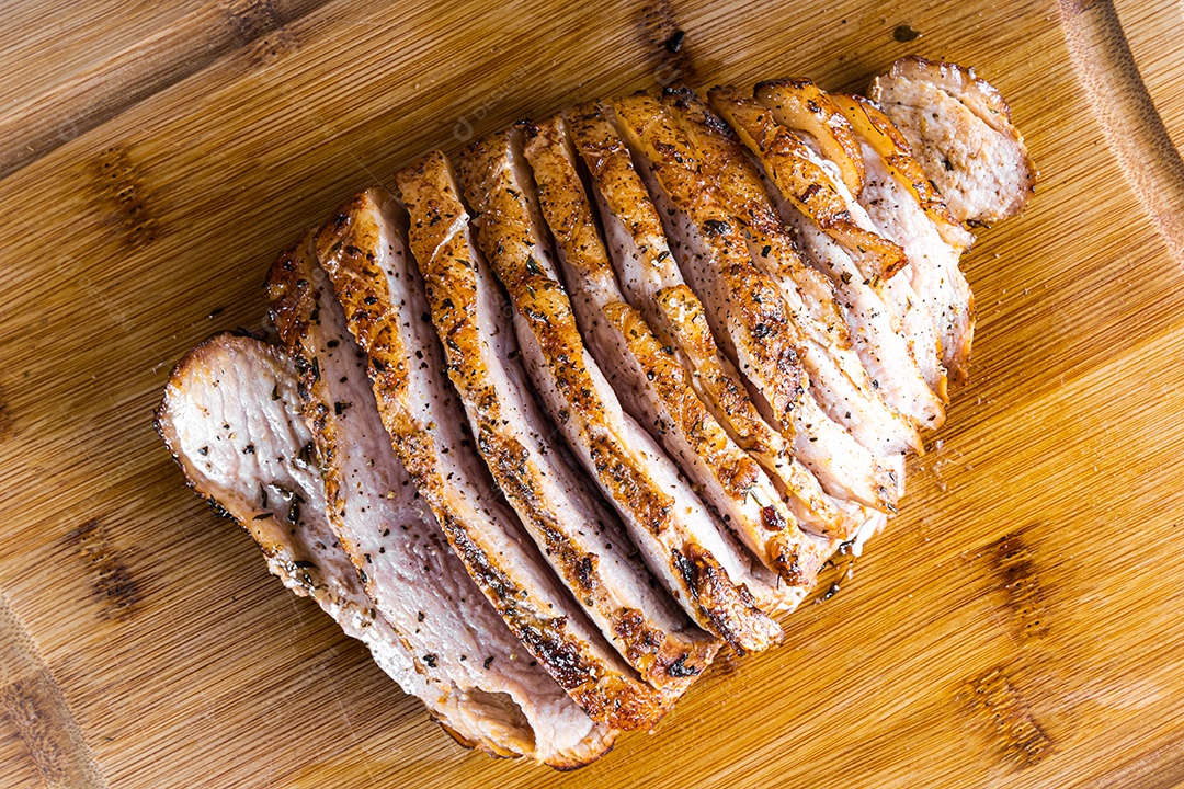 Bife de porco assado em uma tábua de madeira e fatiado