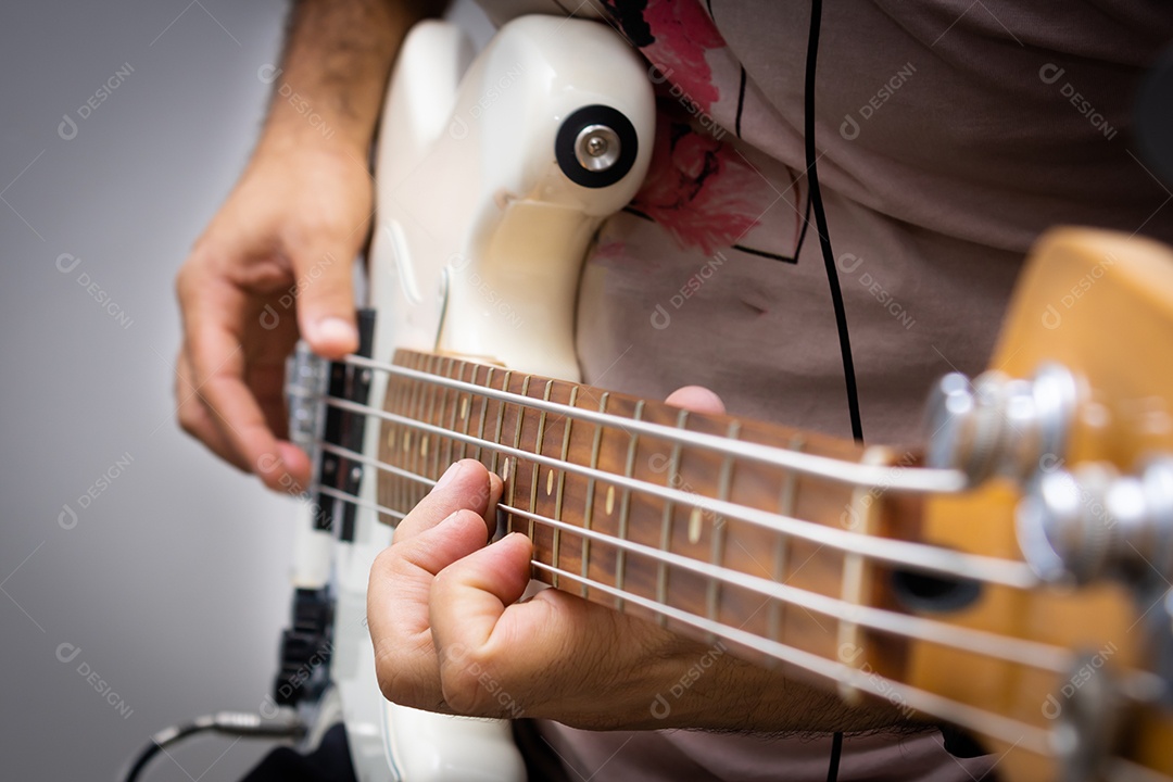 Contrabaixo elétrico branco em solo musical, mostrando em detalhe a mão direita do baixista tocando as cordas.