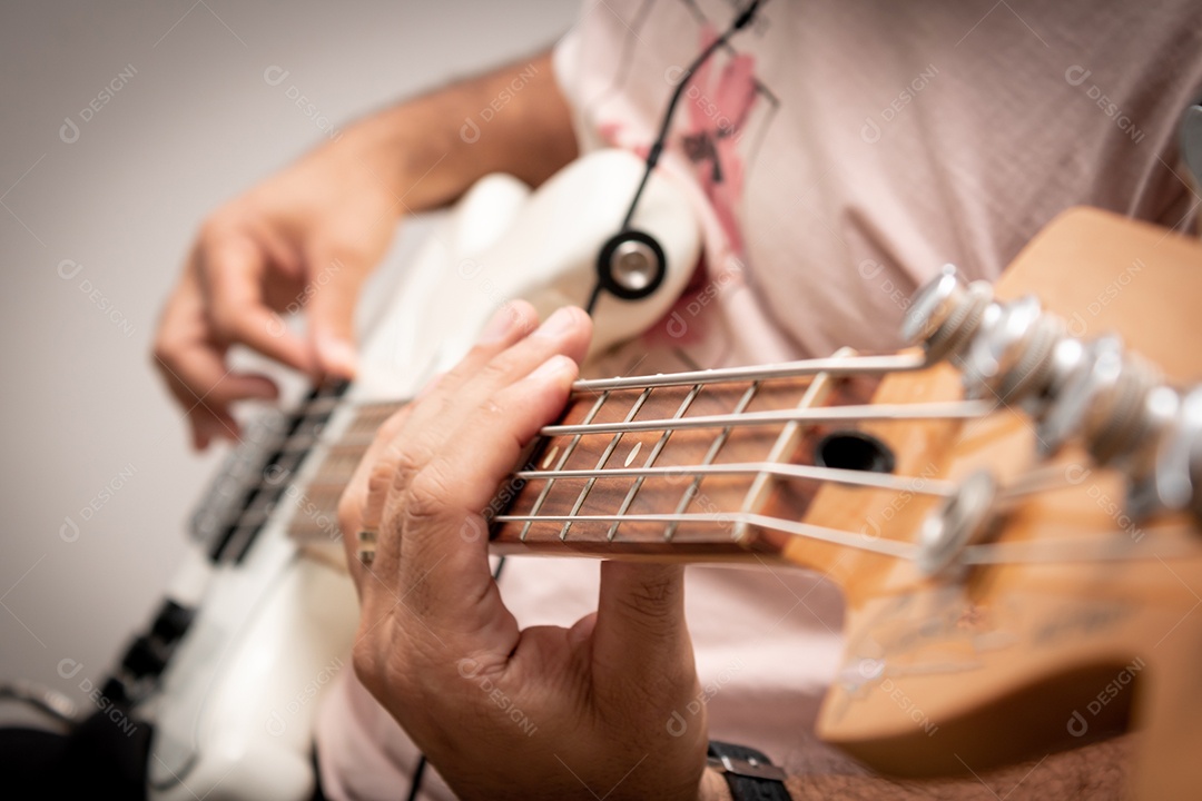 Contrabaixo elétrico branco em solo musical, mostrando em detalhe a mão direita do baixista tocando as cordas.