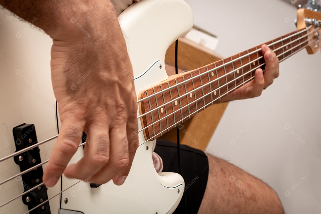 Contrabaixo elétrico branco em solo musical, mostrando em detalhe a mão direita do baixista tocando as cordas.