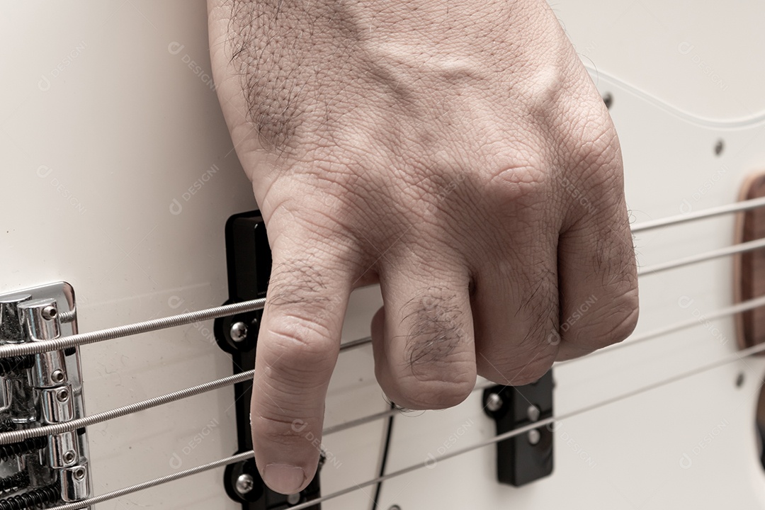 Contrabaixo elétrico branco em solo musical, mostrando em detalhe a mão direita do baixista tocando as cordas.
