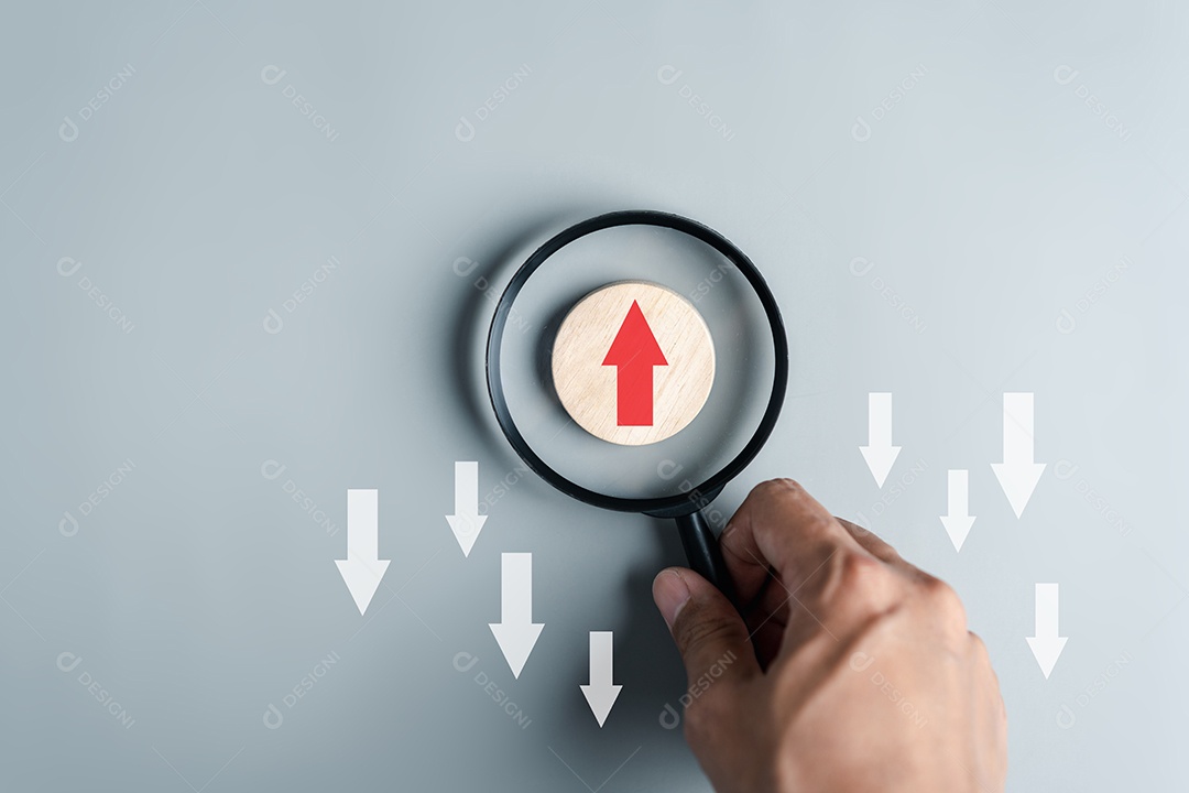 Mão segurando lupa foco para seta vermelha e direção diferente voltada para a direção oposta com seta branca