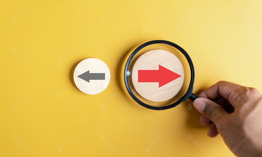 Mão segurando lupa foco para seta vermelha e direção diferente voltada para a direção oposta