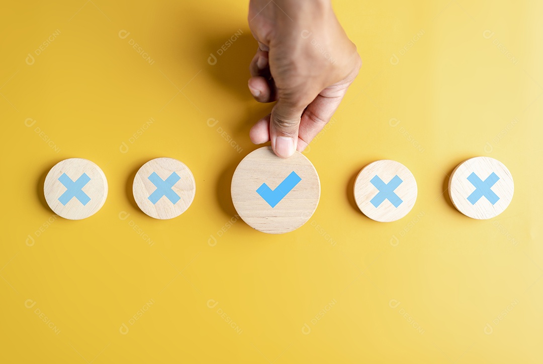 Empresário segurando o ícone correto que entre o ícone errado no bloco de madeira para documento