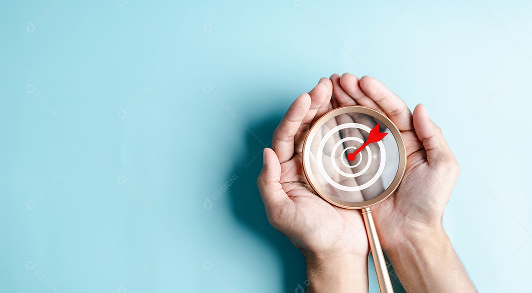 Mãos de negócios segurando o ícone de alvo na lupa, alvo de dardos