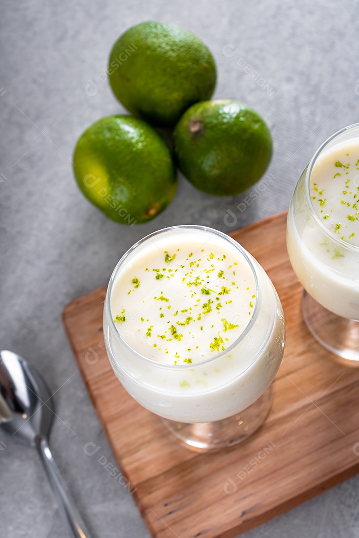 Deliciosa mousse de limão sobre uma tábua de madeira e um fundo de mesa branco, com uma toalha branca em volta e uma colher de metal