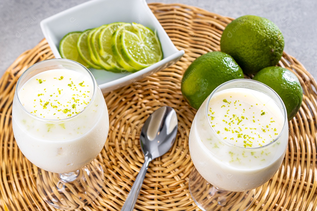 Deliciosa mousse de limão sobre uma tábua de madeira e um fundo de mesa branco, com uma toalha branca em volta e uma colher de metal