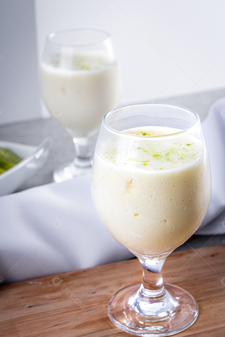 Deliciosa mousse de limão sobre uma tábua de madeira e um fundo de mesa branco, com uma toalha branca em volta e uma colher de metal