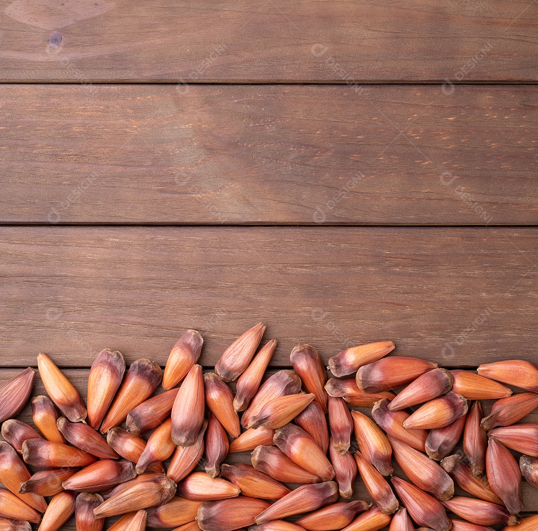 Pinhões ou sementes de pinheiro sobre mesa de madeira com espaço de cópia.