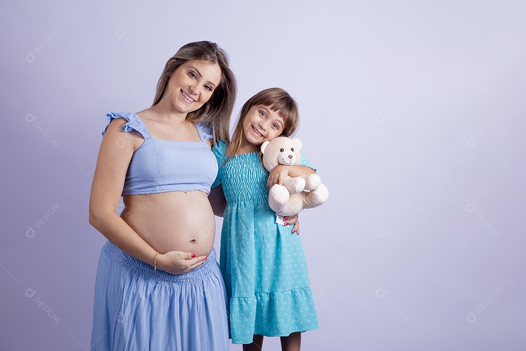 Linda mulher jovem gravida ao lado de sua filha sobre fundo isolado