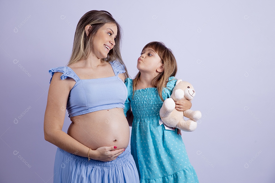 Linda mulher jovem gravida ao lado de sua filha sobre fundo isolado
