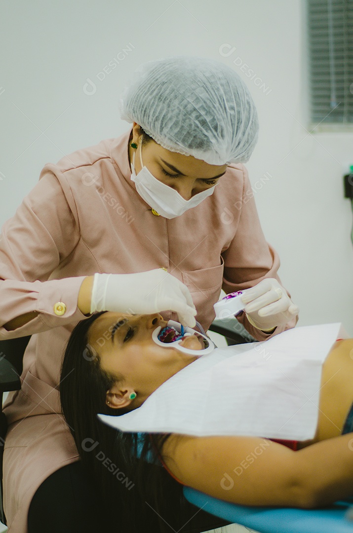 Dentista sobre seu consultorio odontológico atendendo seu paciente