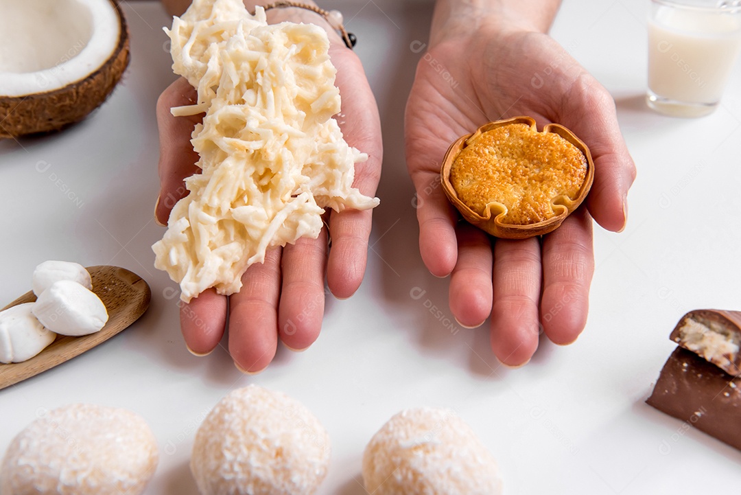 Mãos segurando doce de coco (cocada)