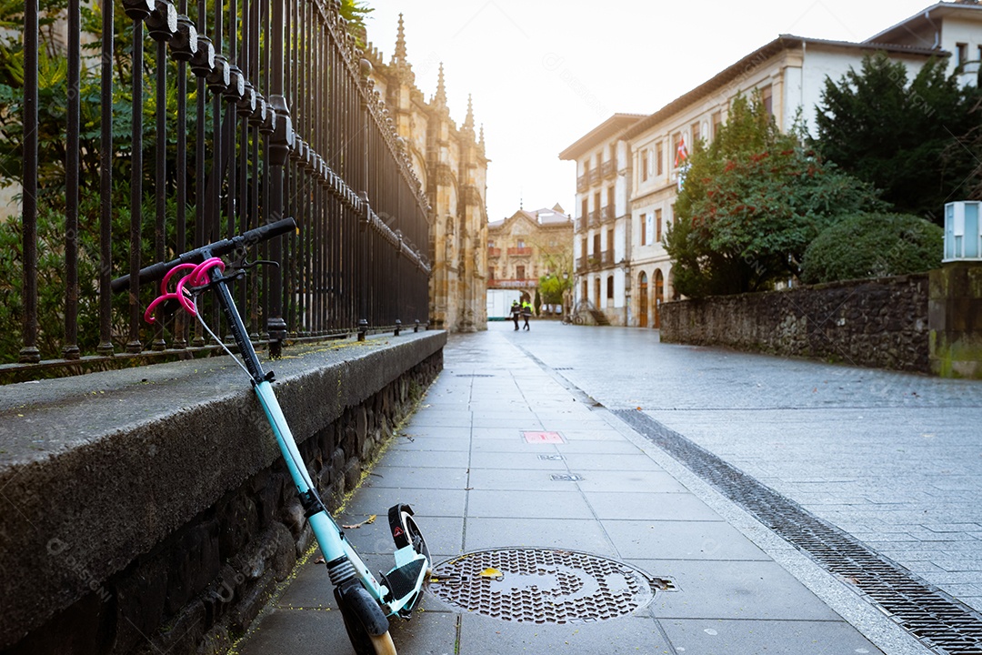 Bicicleta elétrica de scooter apoiada em muro de concreto ao lado de rua na Europa