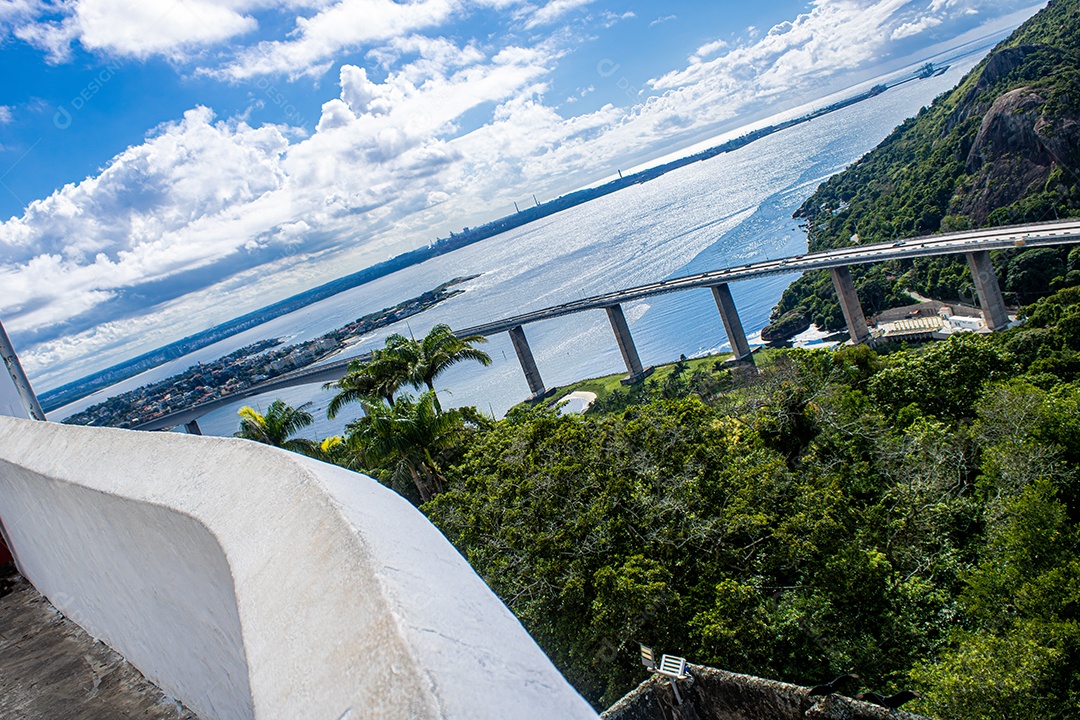 Foto artística que mostra a convergência de linhas em forma de arcos feitos pela parede, ponte e paisagem.