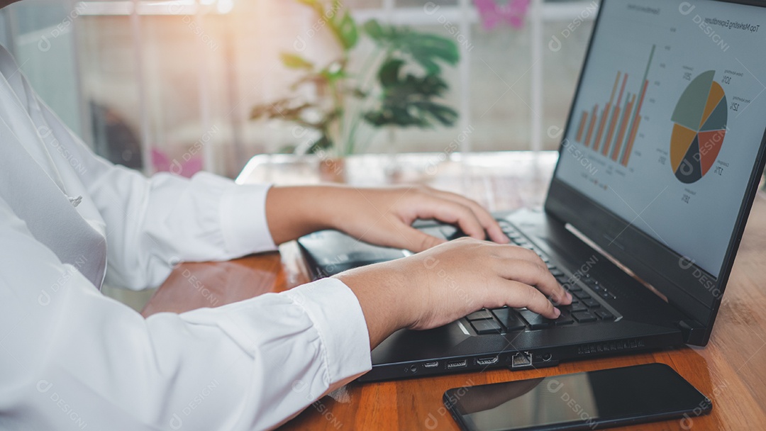Empresária usando computador portátil na mesa de madeira e ela está olhando para o gráfico exibido na tela do computador.