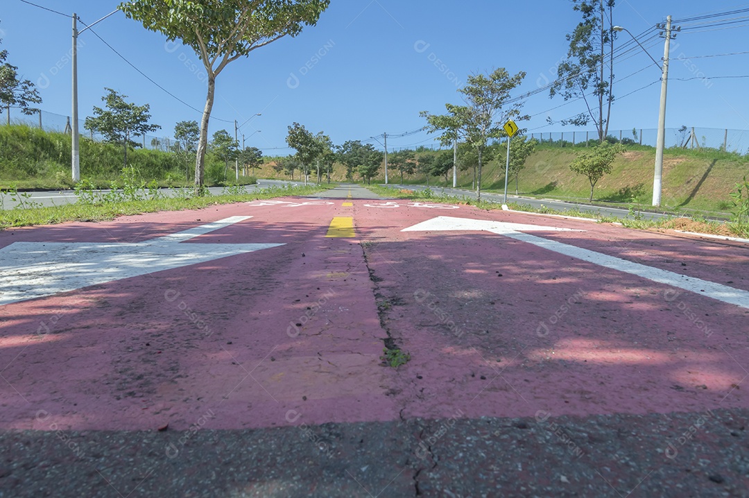 Ciclovia com asfalto ao seu redor, sinais na ciclovia em um dia ensolarado.