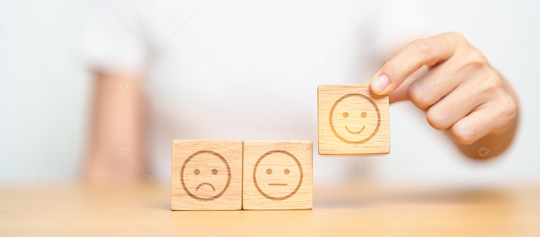 Mão escolhendo o rosto sorridente do bloco Emoção para avaliação do cliente, boa experiência, feedback positivo, satisfação, pesquisa, avaliação