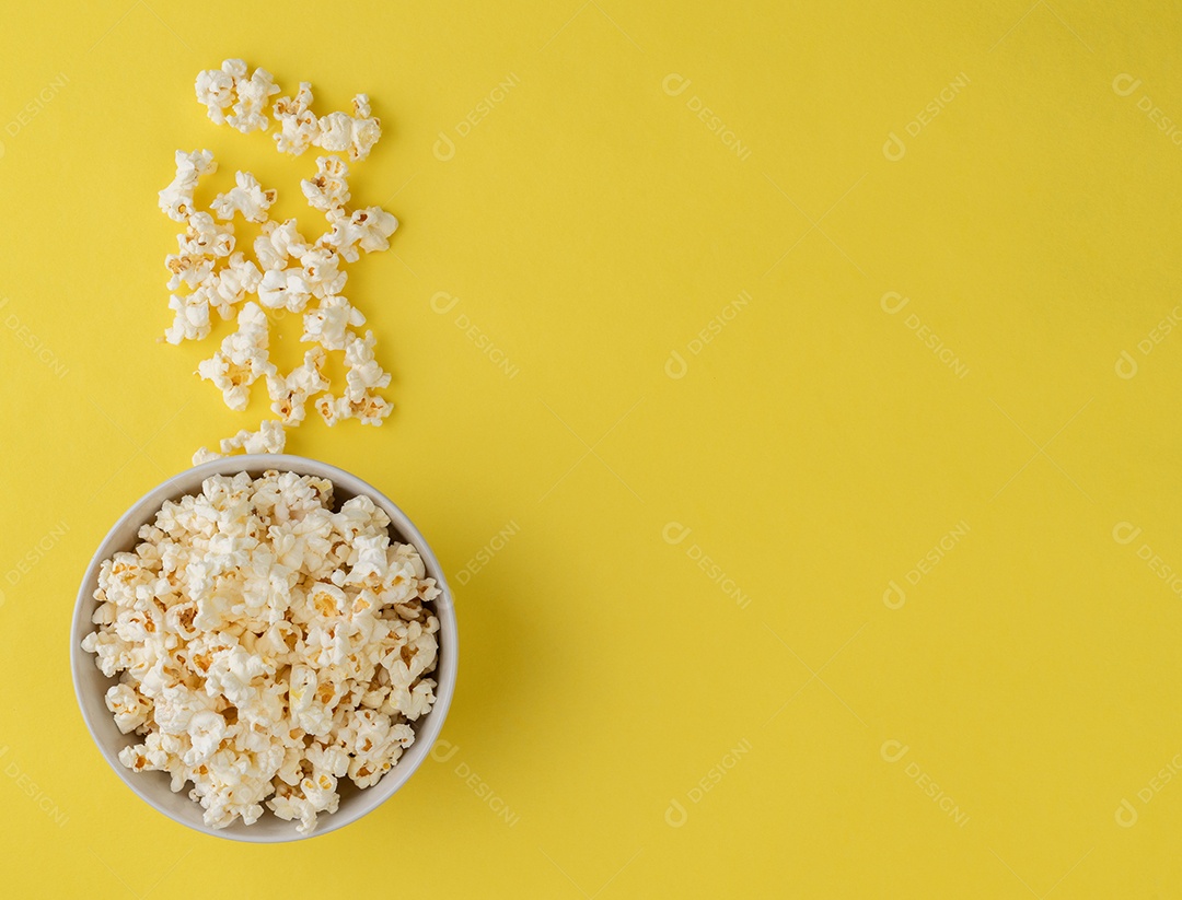 Pipocas em uma tigela sobre fundo amarelo com espaço de cópia.