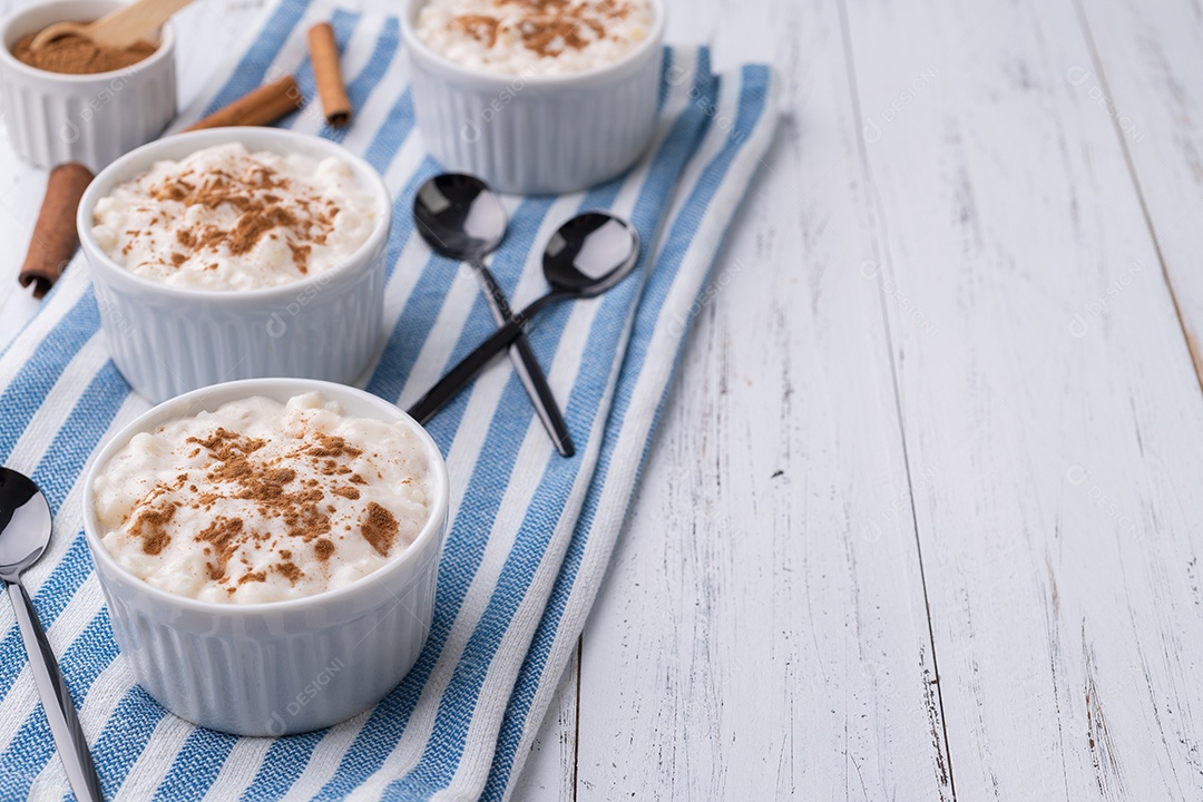 Canjica ou munguza, típico creme doce de milho branco brasileiro com canela sobre mesa de madeira com espaço para cópia.