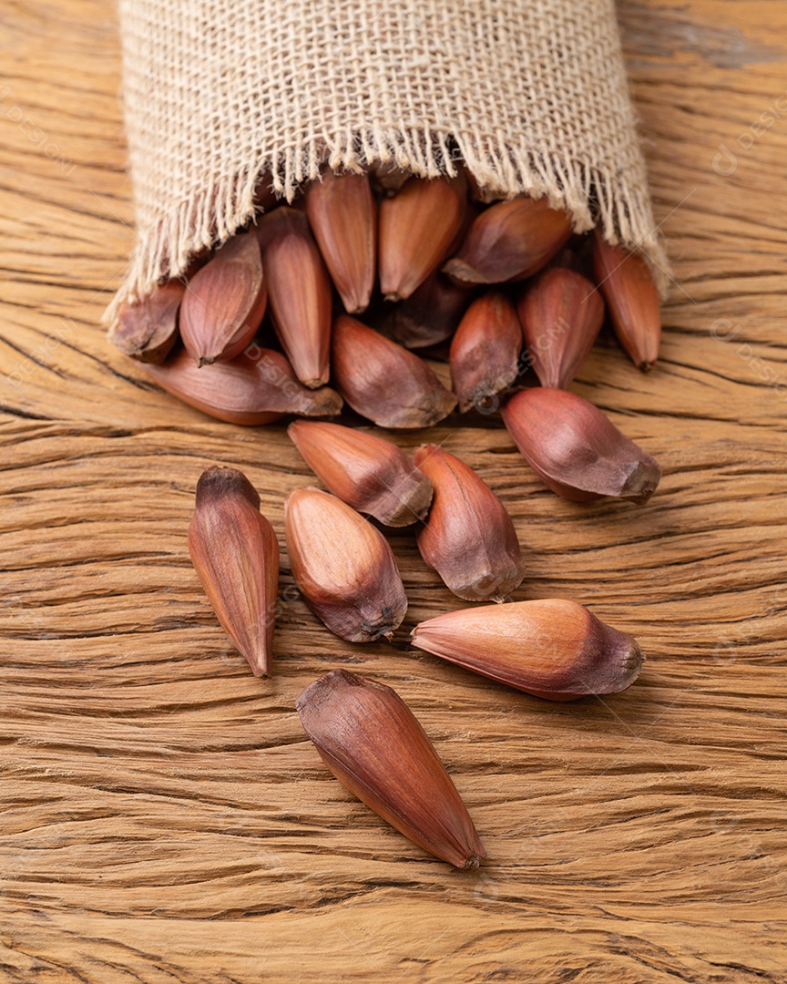 Pinhões ou sementes de pinheiro em um saco sobre a mesa de madeira.