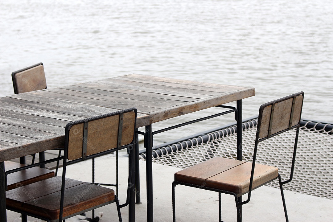 Mesa e cadeira vazias de madeira vintage ao ar livre no restaurante da cafeteria perto do rio