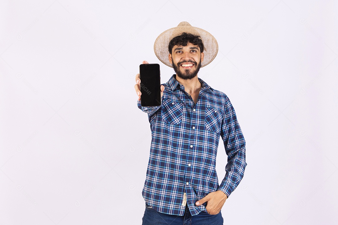 Homem jovem barbudo fantasiada celebrando festas juninas segurando celular smartphone