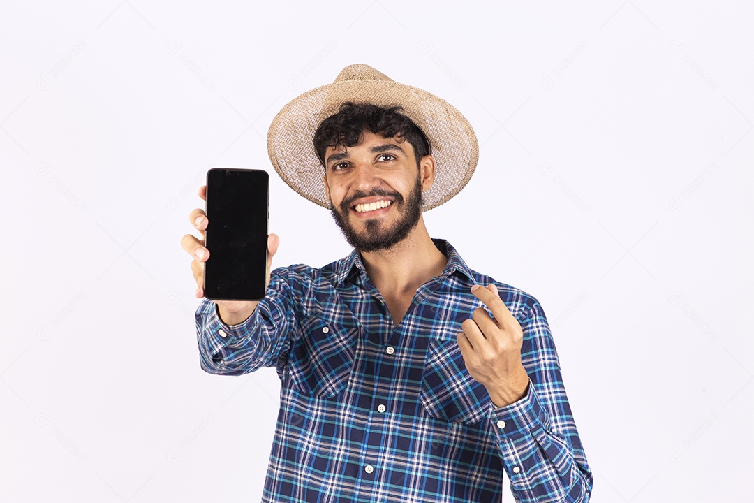 Homem jovem barbudo fantasiada celebrando festas juninas segurando celular smartphone