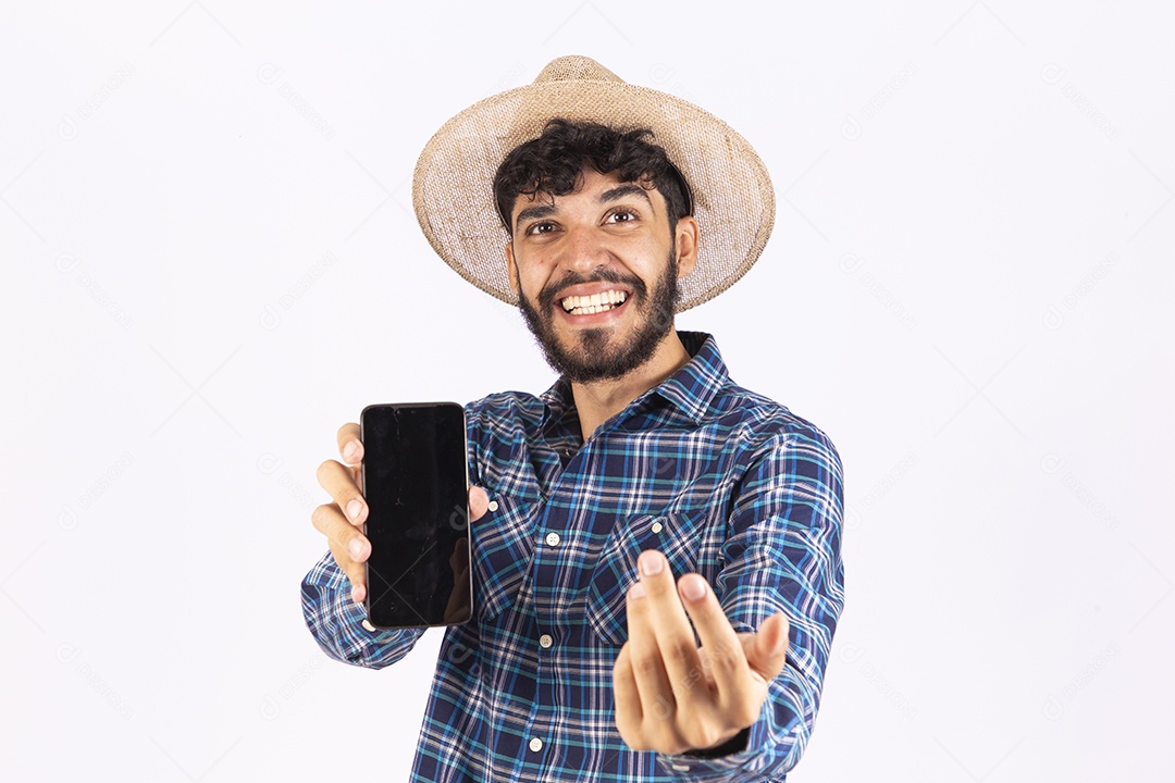 Homem jovem barbudo fantasiada celebrando festas juninas segurando celular smartphone