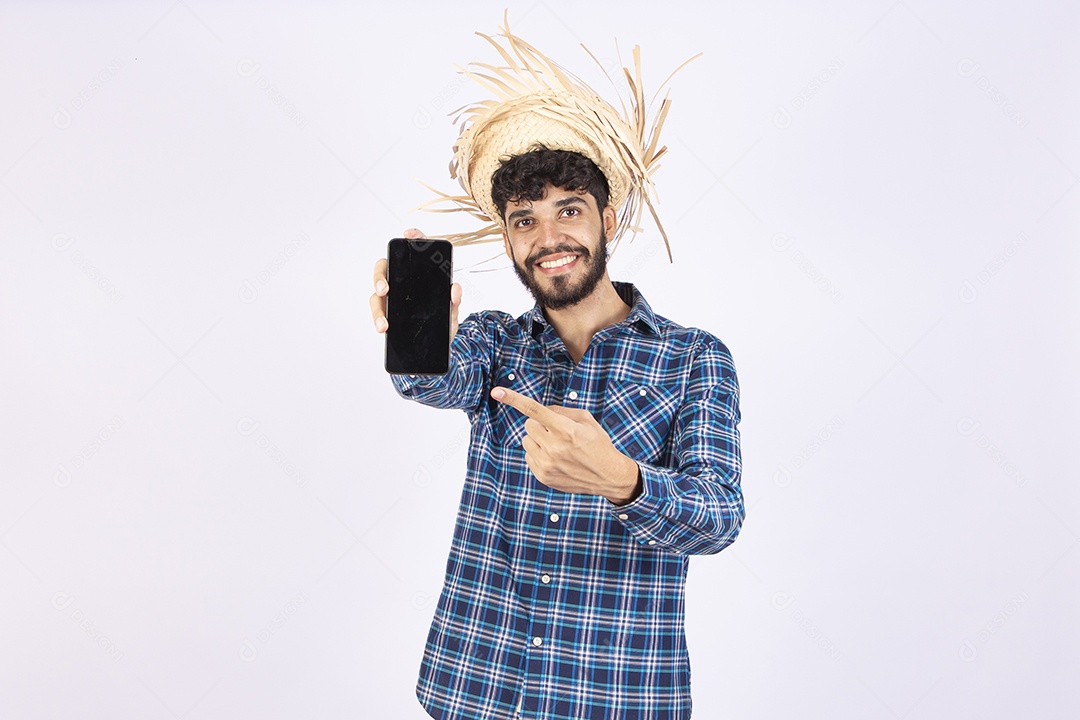 Homem jovem barbudo fantasiada celebrando festas juninas segurando celular smartphone