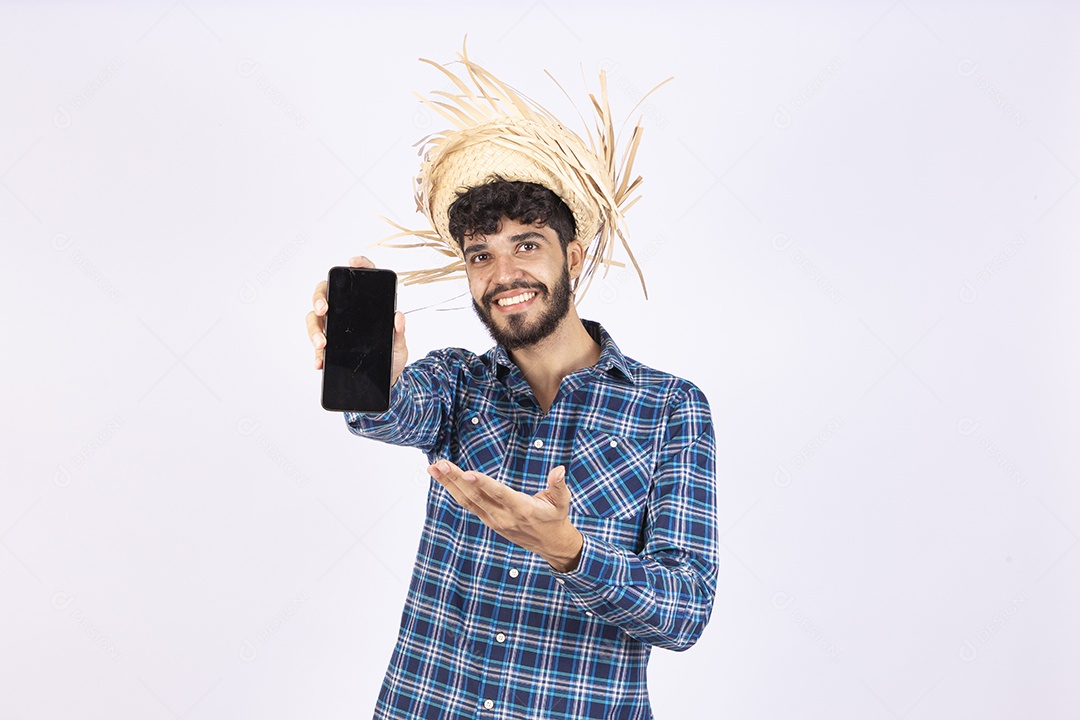 Homem jovem barbudo fantasiada celebrando festas juninas segurando celular smartphone