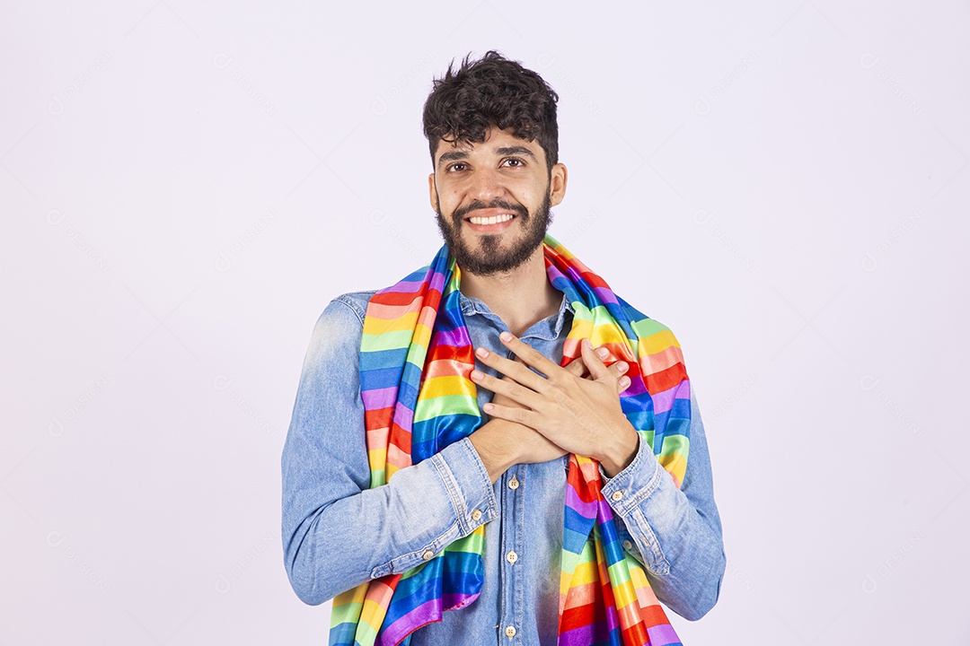 Homem jovem feliz e sorridente sobre fundo isolado branco segurando bandeira LGBTQI+