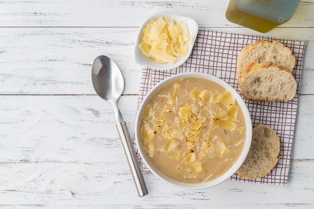 Sopa de cebola com queijo em uma tigela com fatias de pão e temperos sobre mesa de madeira com espaço para cópia.