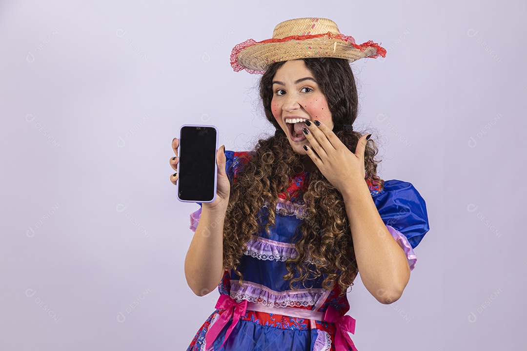 Linda mulher jovem fantasiada celebrando festas juninas segurando celular smartphone