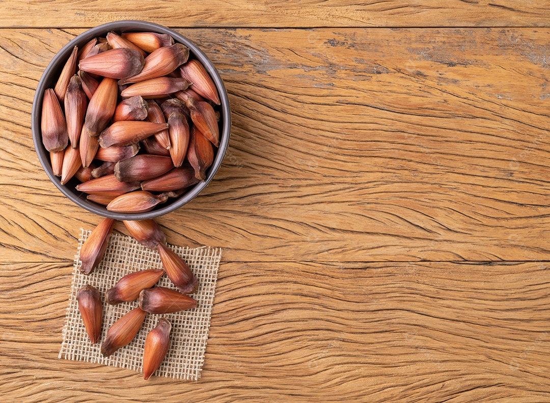 Pinhões ou sementes de pinheiro em uma tigela sobre a mesa de madeira com espaço de cópia.