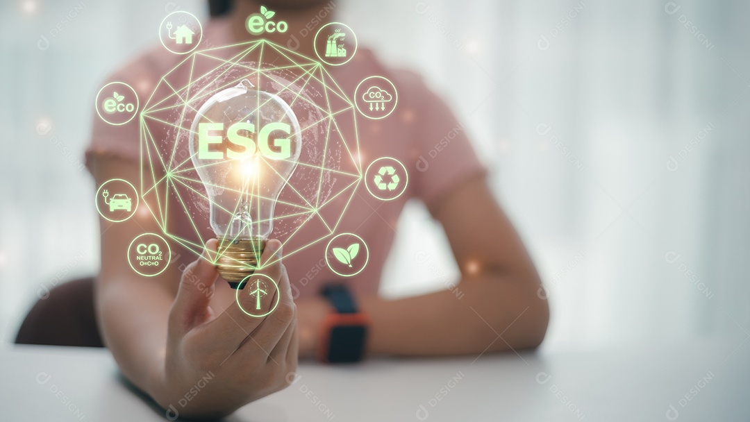 Mão de empresária segurando lâmpada com ícone ESG na tela virtual, conceito de governança ambiental, social e corporativa ESG.