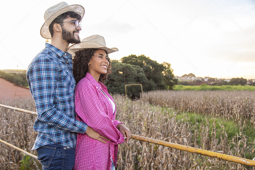 Casal feliz e sorridente sobre plantação