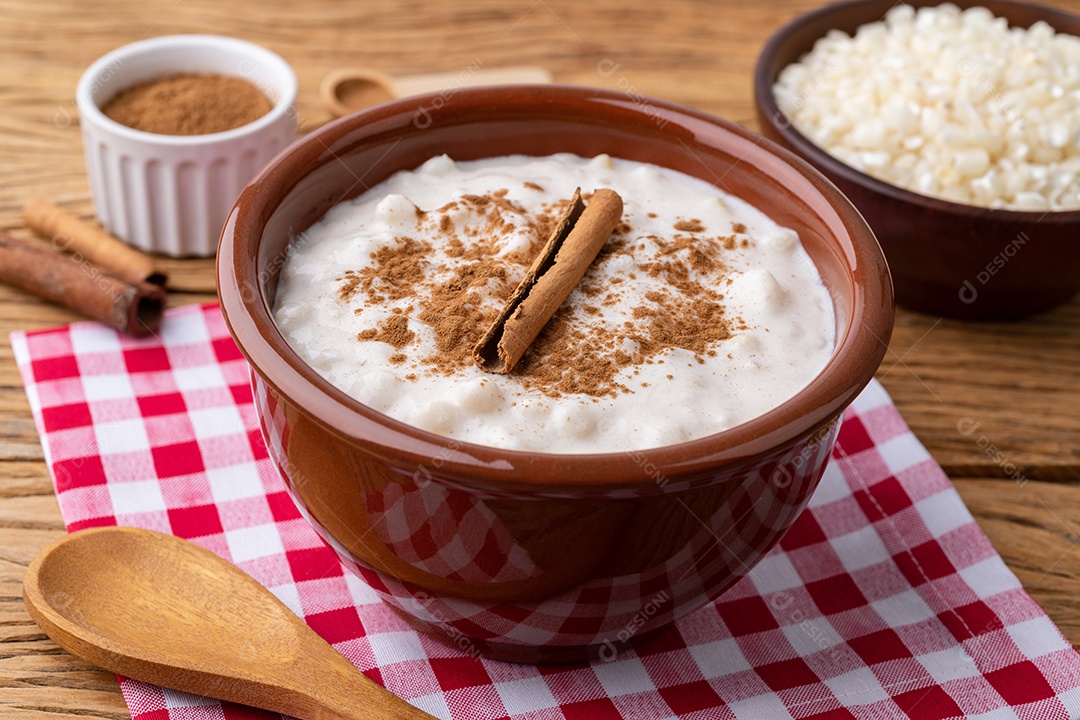 Canjica ou munguza, típico creme doce de milho branco brasileiro com canela sobre mesa de madeira.