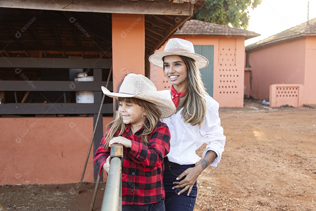 Mãe linda ao lado de sua filha sobre uma fazenda