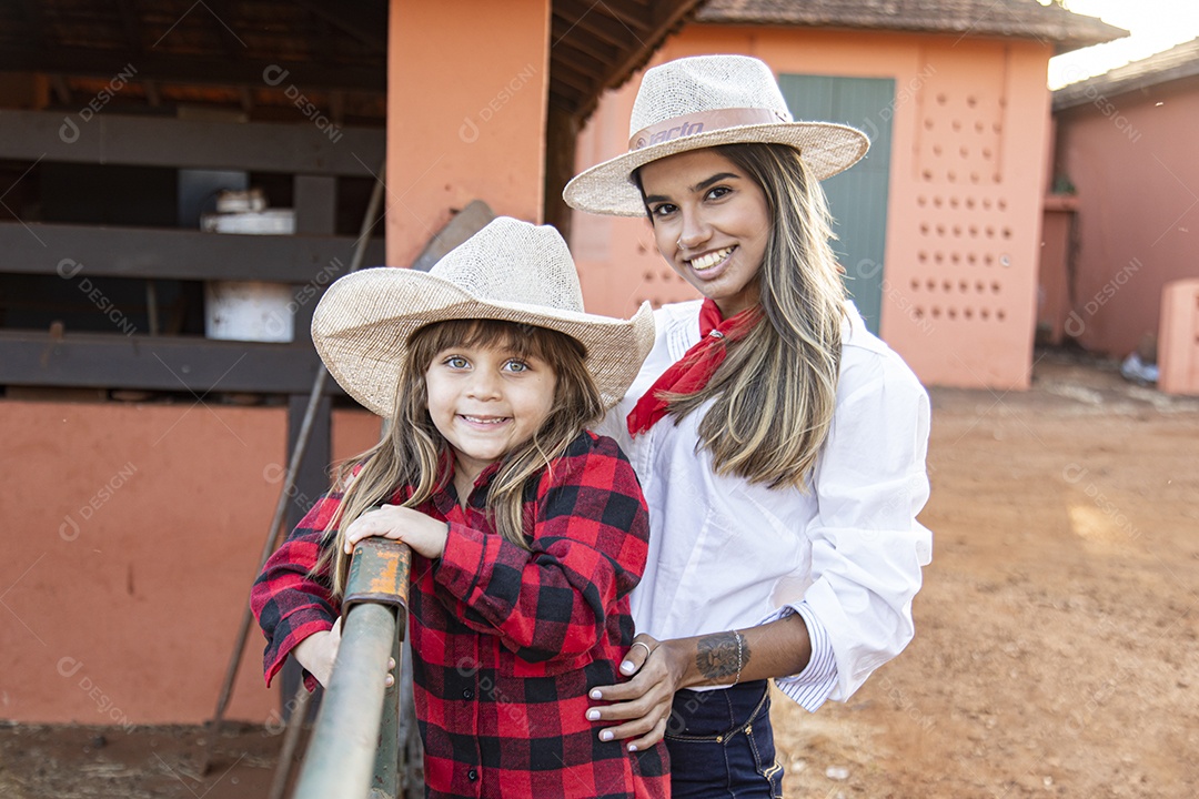 Mãe linda ao lado de sua filha sobre uma fazenda