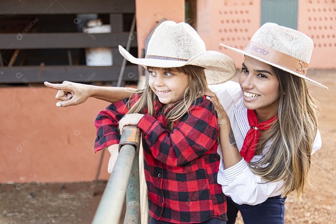 Mãe linda ao lado de sua filha sobre uma fazenda