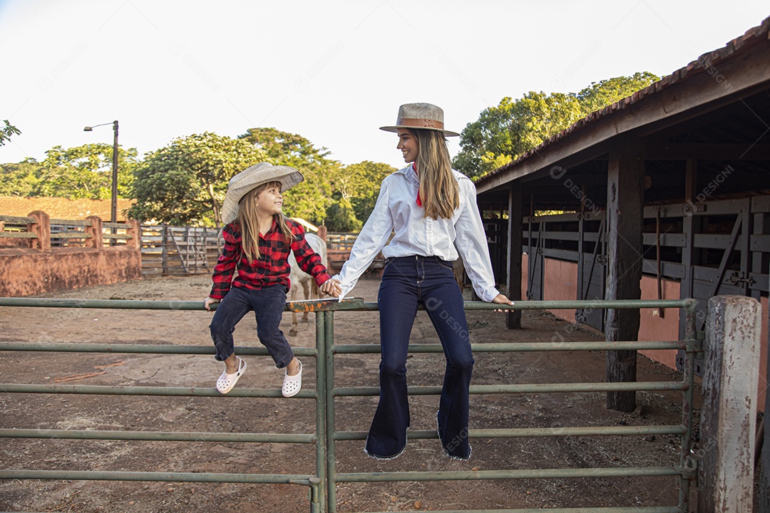 Mãe linda ao lado de sua filha sobre uma fazenda
