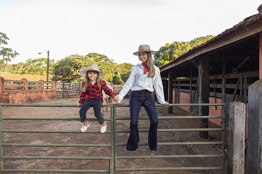 Mãe linda ao lado de sua filha sobre uma fazenda