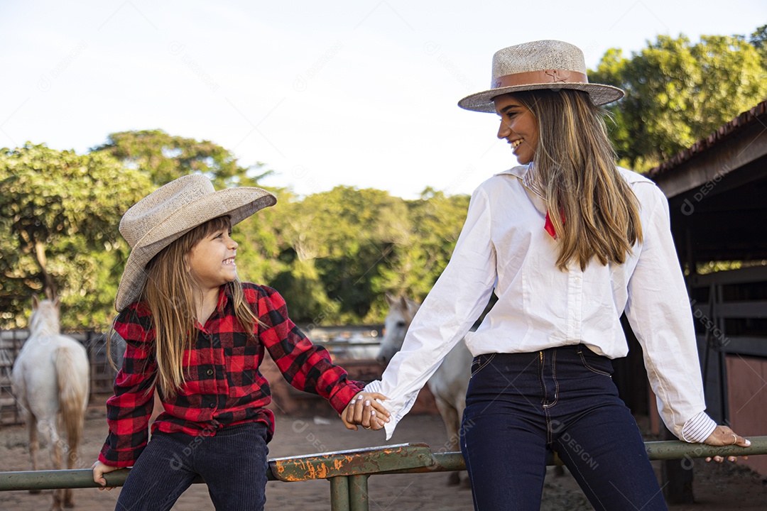 Mãe linda ao lado de sua filha sobre uma fazenda
