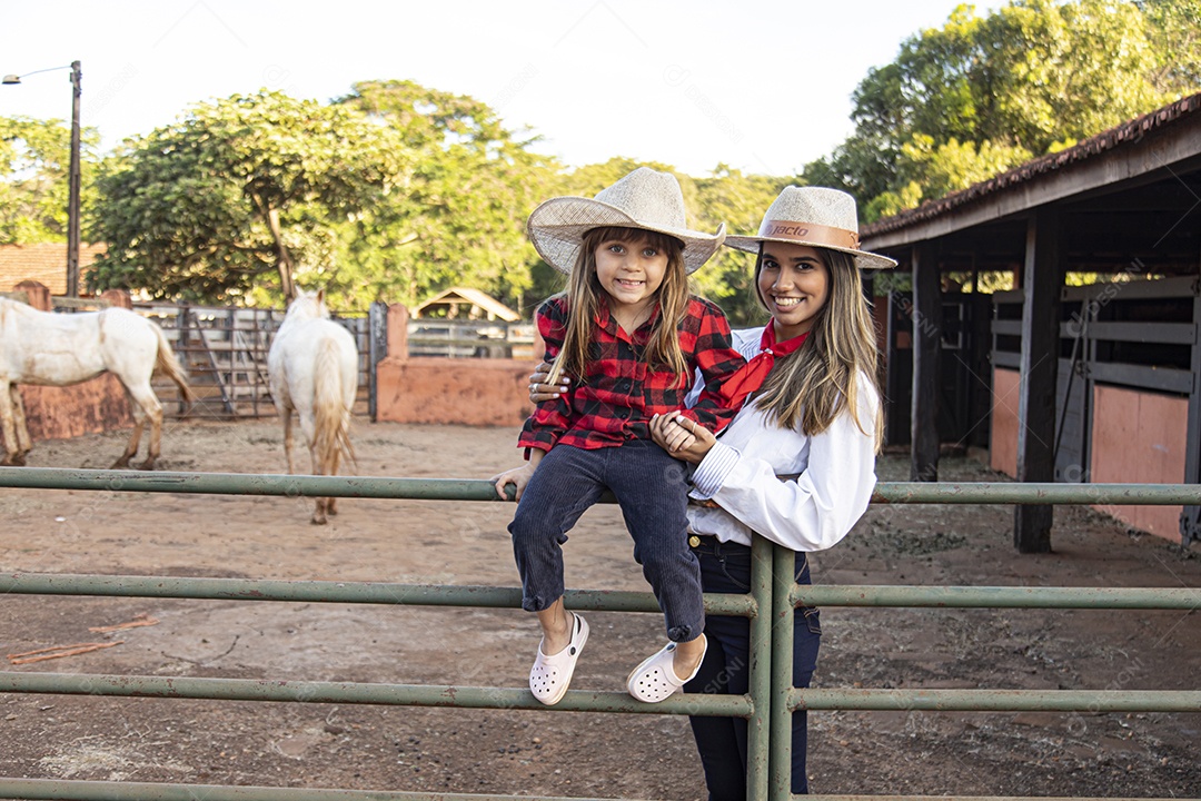 Mãe linda ao lado de sua filha sobre uma fazenda